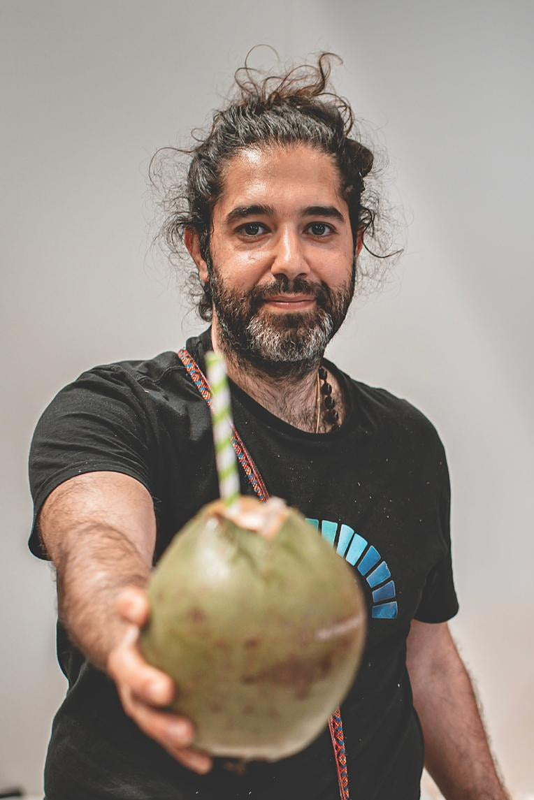 Man holding a coconut with a banner in the background displaying health benefits.